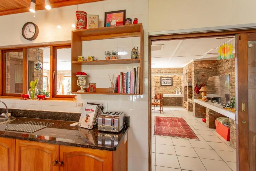 Warm kitchen with wooden cabinetry, dark countertop, and open shelving displaying decor