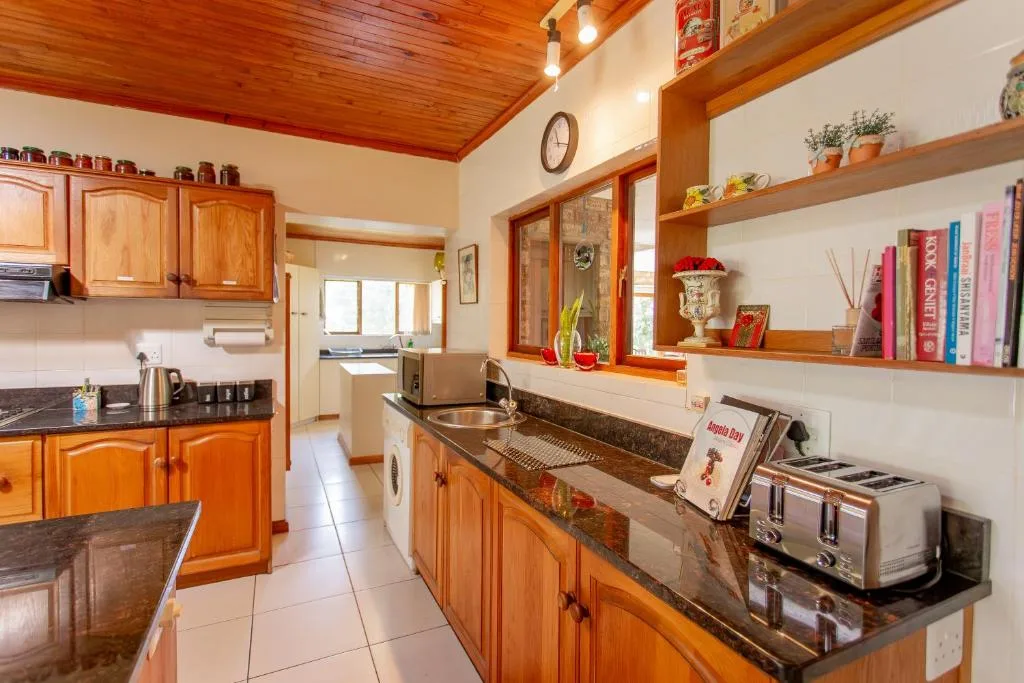 Spacious kitchen with wooden cabinetry, dark countertops, and open shelving