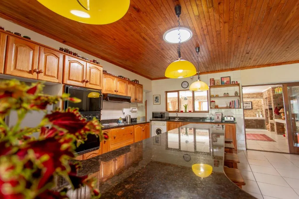Spacious kitchen with wooden cabinetry, yellow pendant lights, granite countertops