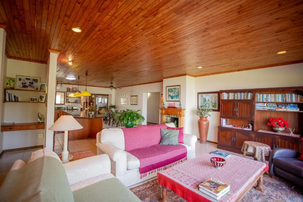 Spacious lounge with pink sofa, wooden ceiling, and bookshelves