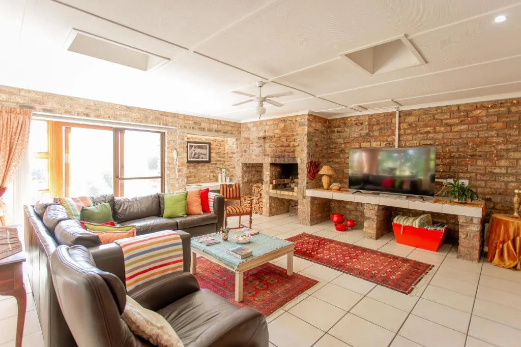 Spacious lounge with leather sofas, fireplace, and exposed brick walls