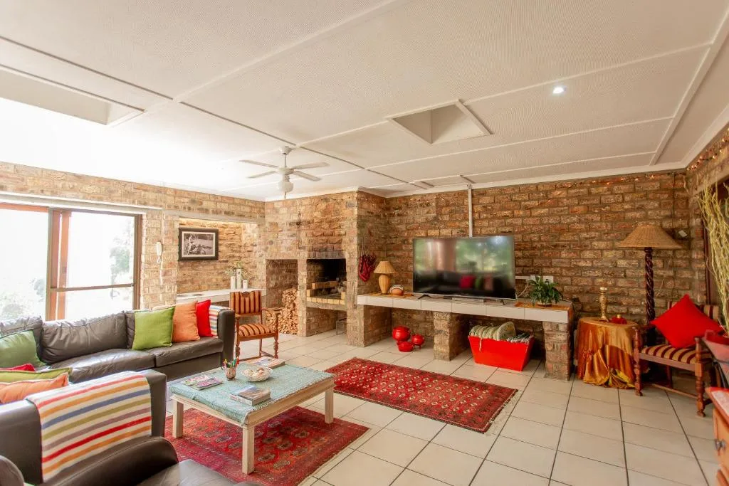 Spacious brick lounge with grey sofa, fireplace, TV, and colorful accents
