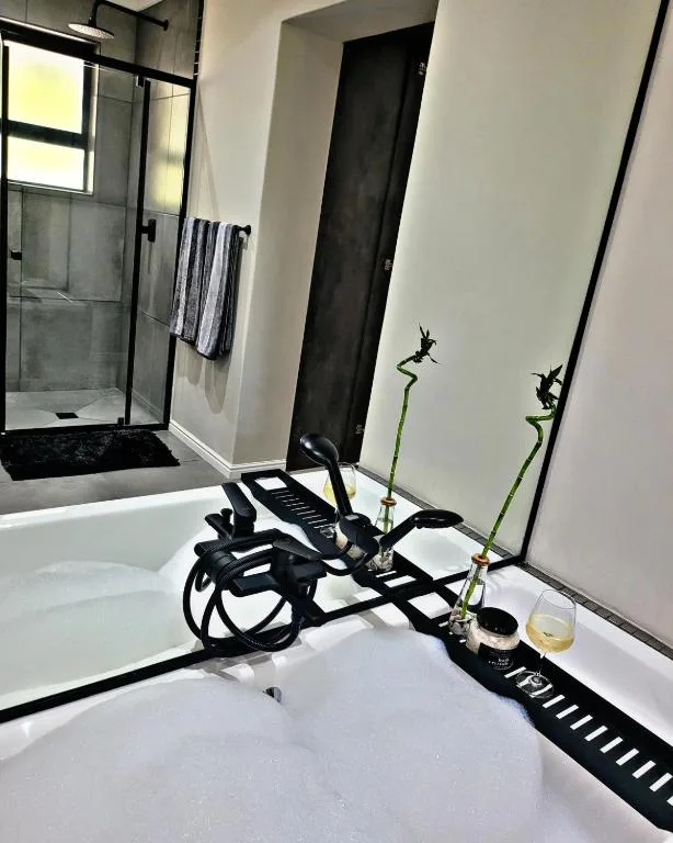 Modern bathroom with walk-in shower, white vanity, decorative bamboo and black accessories