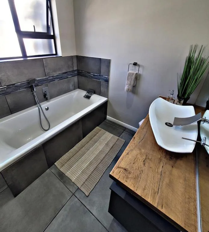 Modern bathroom with bathtub, freestanding sink, and dark tile accents