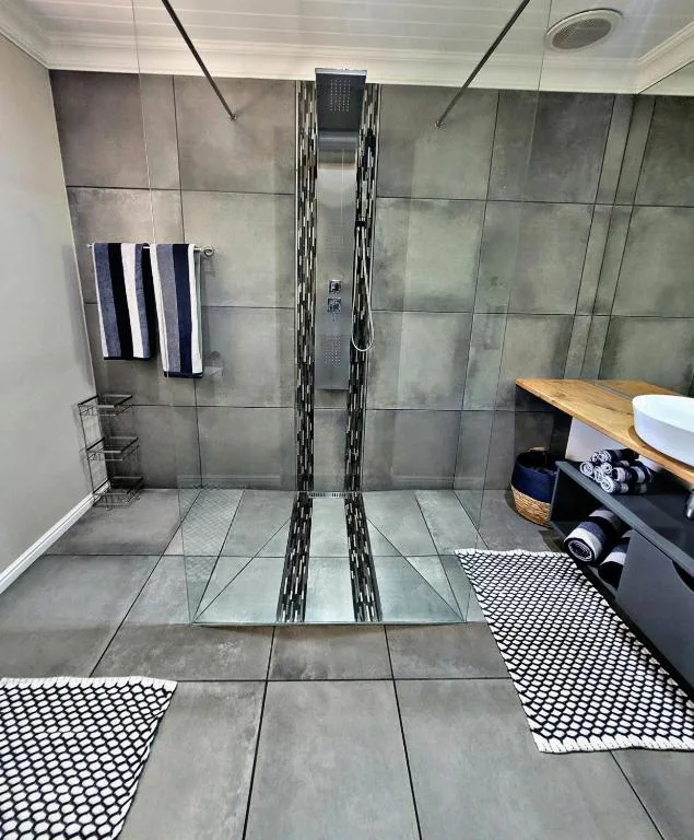 Modern bathroom with walk-in shower, grey tiling, and heated towel rail