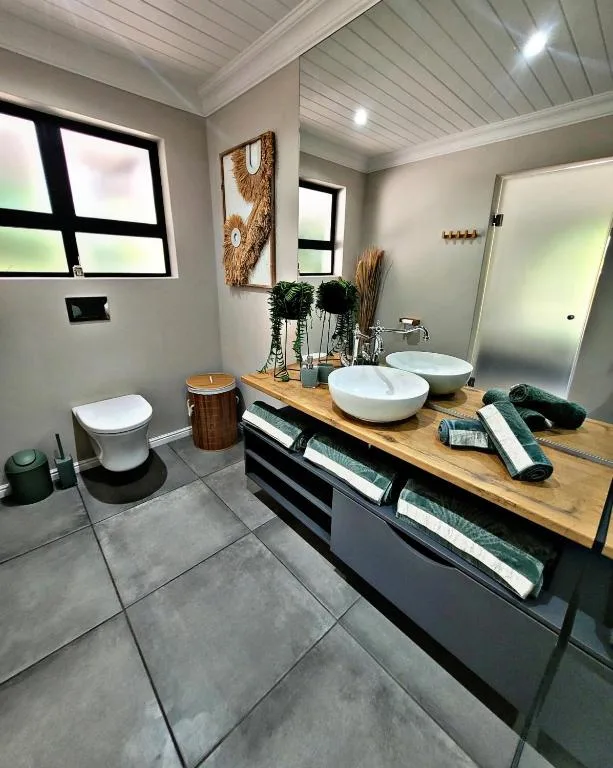 Modern bathroom with dual vessel sinks, wooden countertop, and sleek fixtures