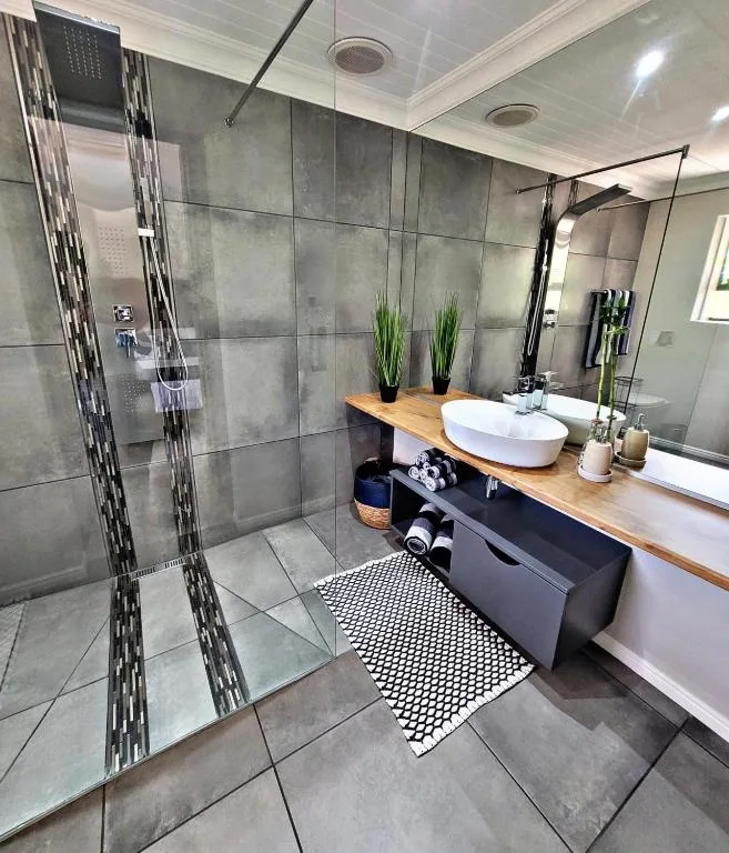 Modern bathroom with walk-in shower, dual vanity sinks, and wooden countertop