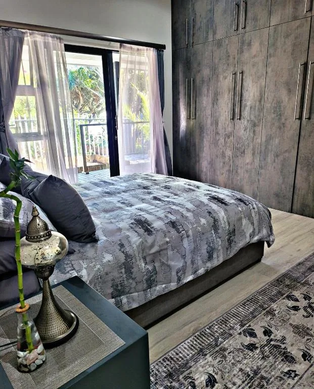 Modern bedroom with patterned bedding, dark wardrobe, and garden views