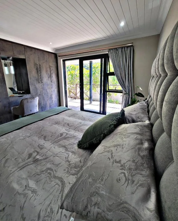 Modern bedroom with queen bed, upholstered headboard, and garden view doors