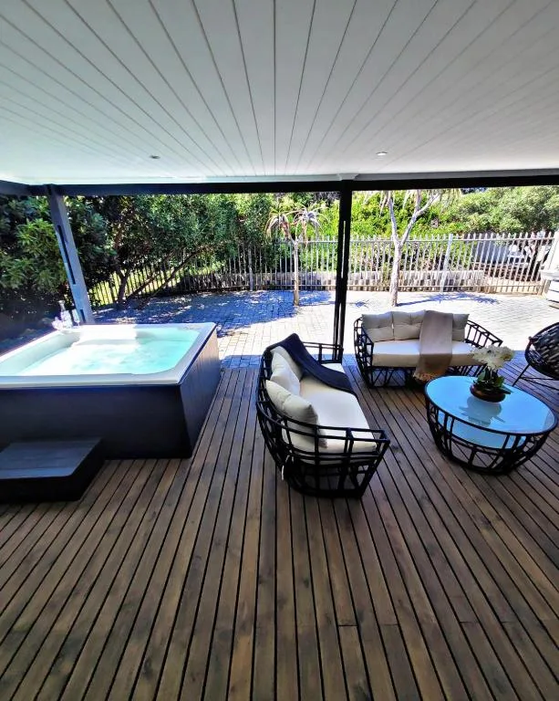 Covered deck with hot tub, lounge seating, and pool views