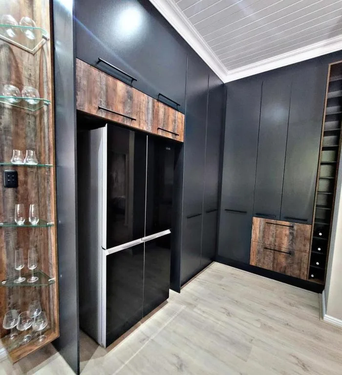 Modern dark kitchen with sleek black refrigerator and rustic wood cabinetry