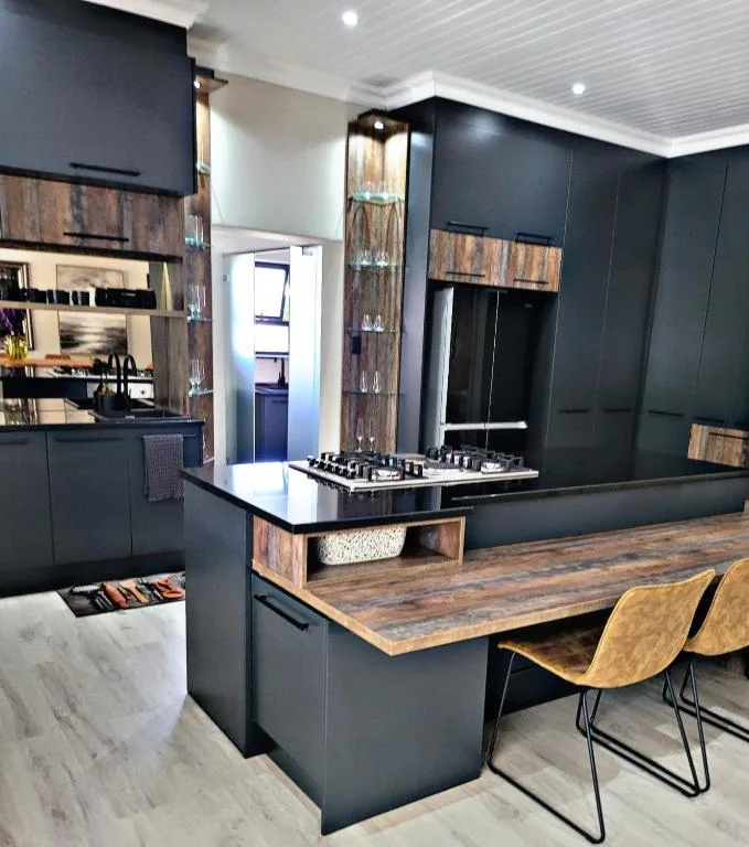 Modern black kitchen with wood accents, island counter, and bar seating
