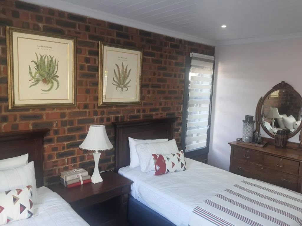 Bedroom with exposed brick wall, double bed, and botanical artwork