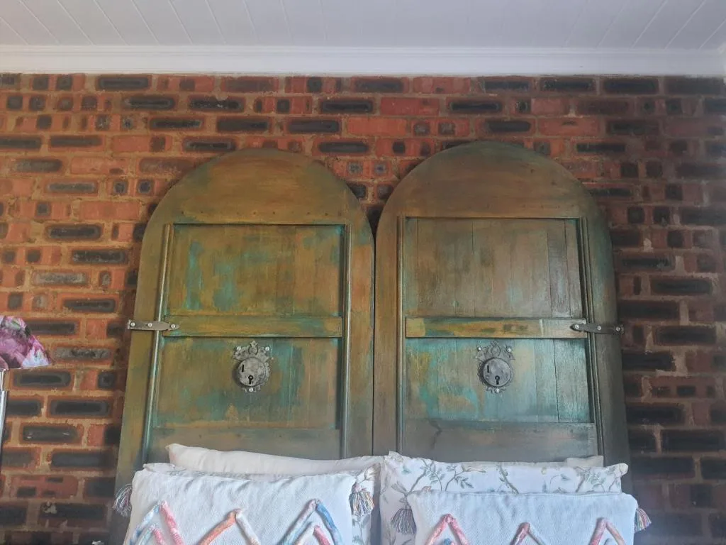 Vintage arched wooden doors with patina against red brick wall