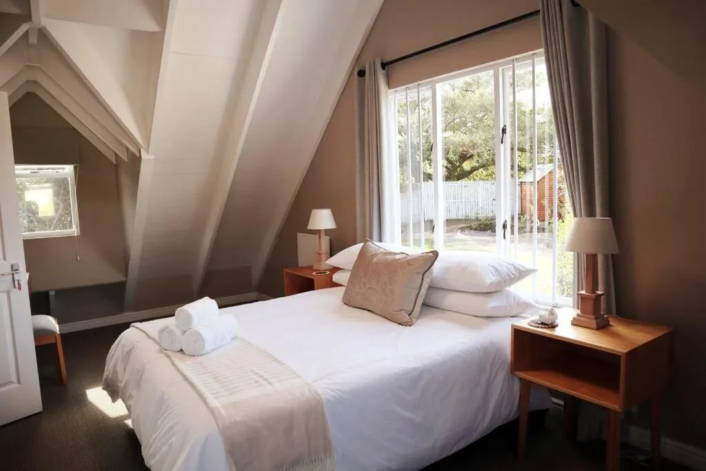 Bright bedroom with queen bed, vaulted ceiling, and garden views through French doors