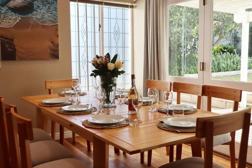 Wooden dining table set with place settings and fresh flowers indoors