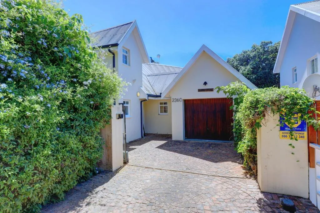White cottage with metal roof and red garage door, garden entrance