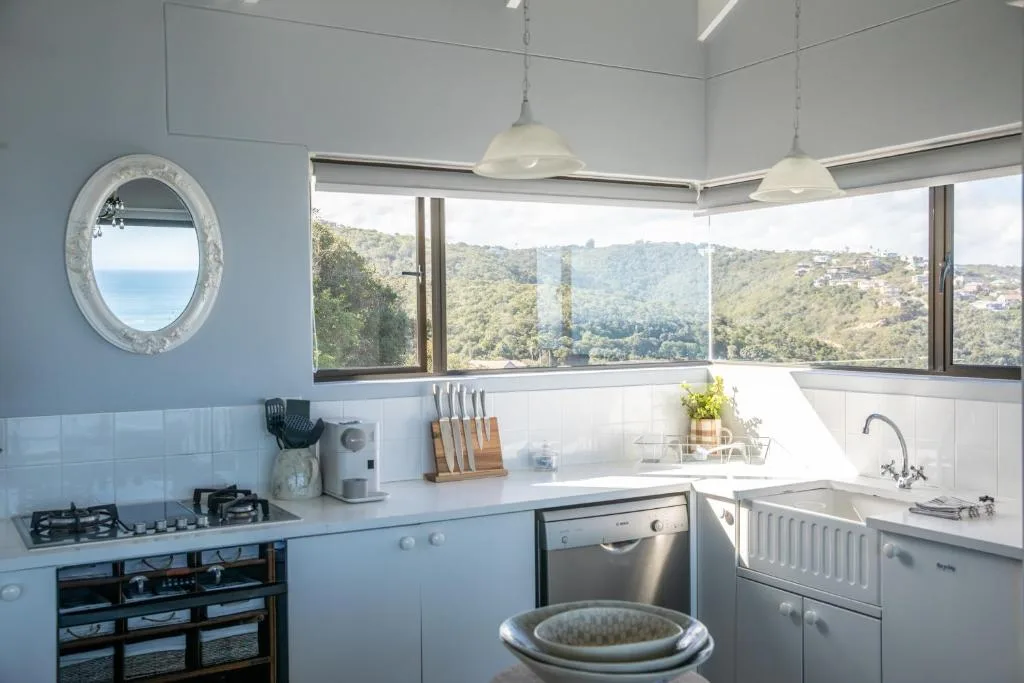 Modern kitchen with gas stove, sink, and panoramic mountain views through large windows