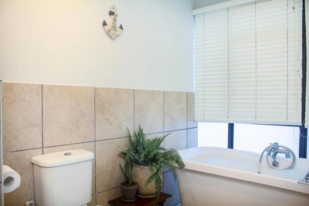 Bathroom with toilet, bathtub, and potted plant decoration