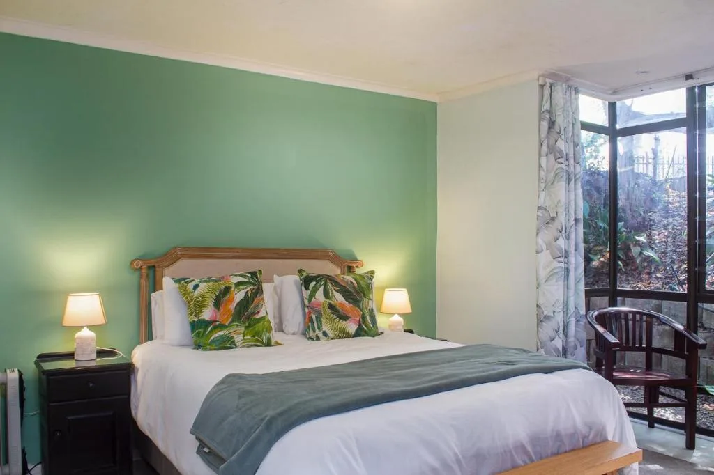 Bright green bedroom with wooden bed frame and garden view doors