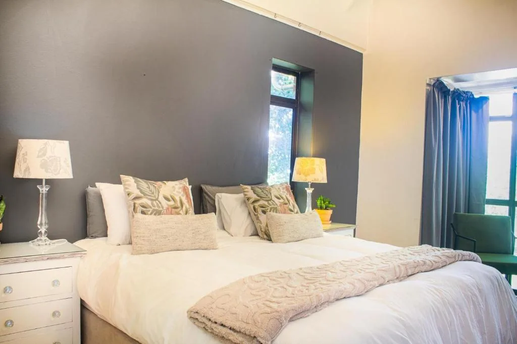 Spacious bedroom with queen bed, patterned pillows, and bedside lamps