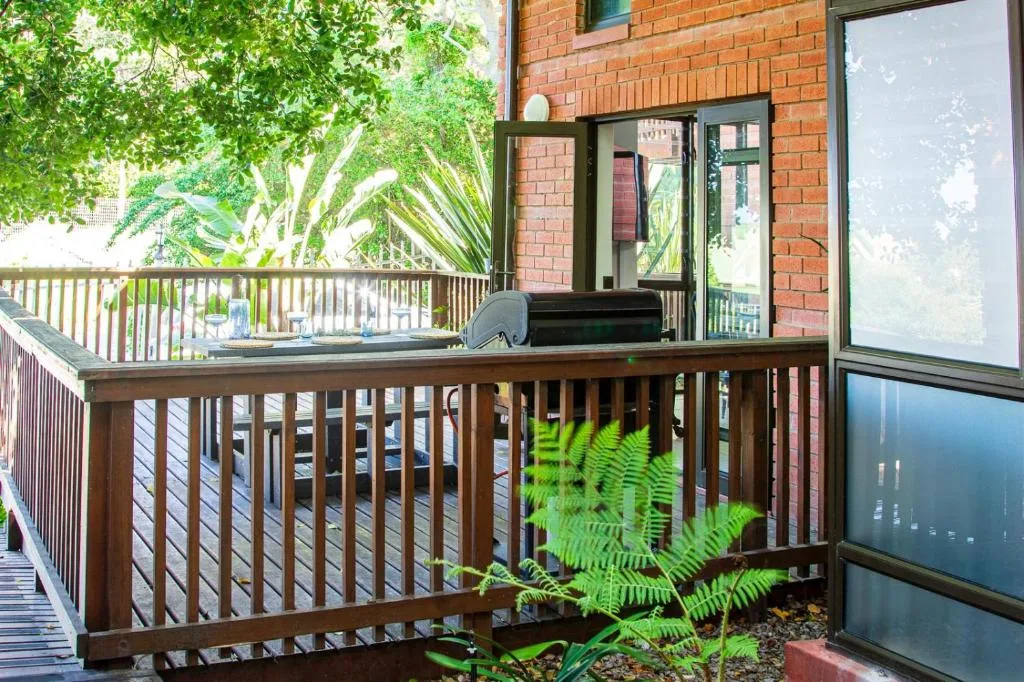 Wooden deck with railing, ferns, and brick building entrance