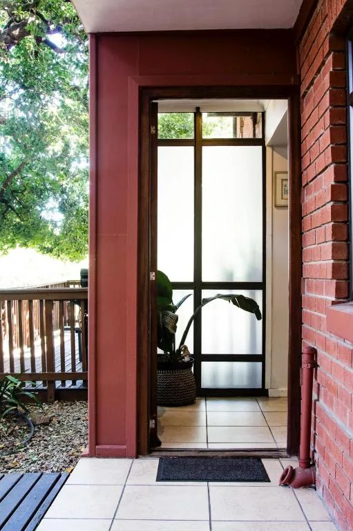Dark burgundy exterior entrance with black-framed glass door and brick wall