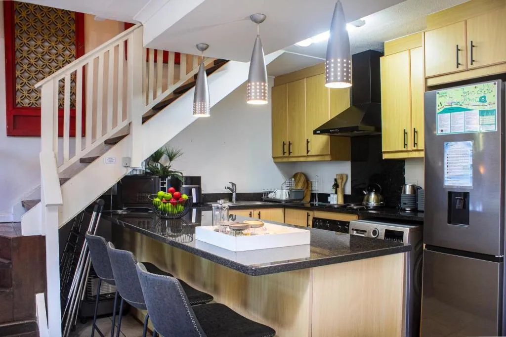 Modern kitchen with yellow cabinetry, black countertops, and stainless steel appliances