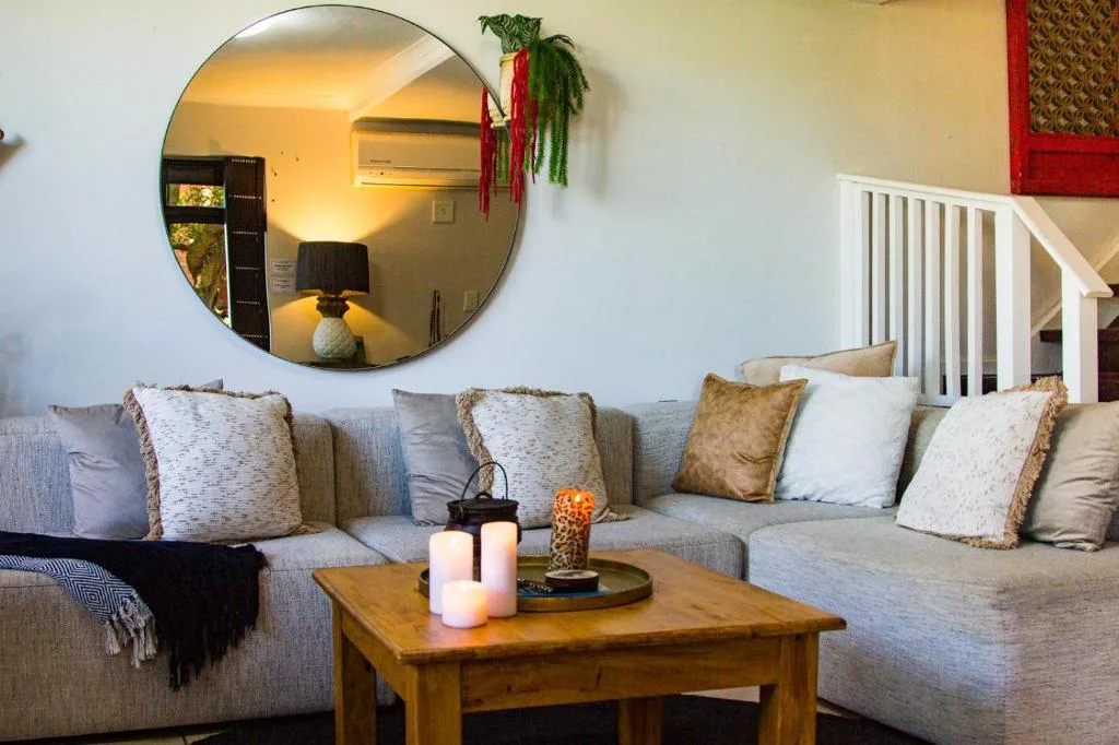 Contemporary lounge with neutral sectional sofa and decorative round mirror