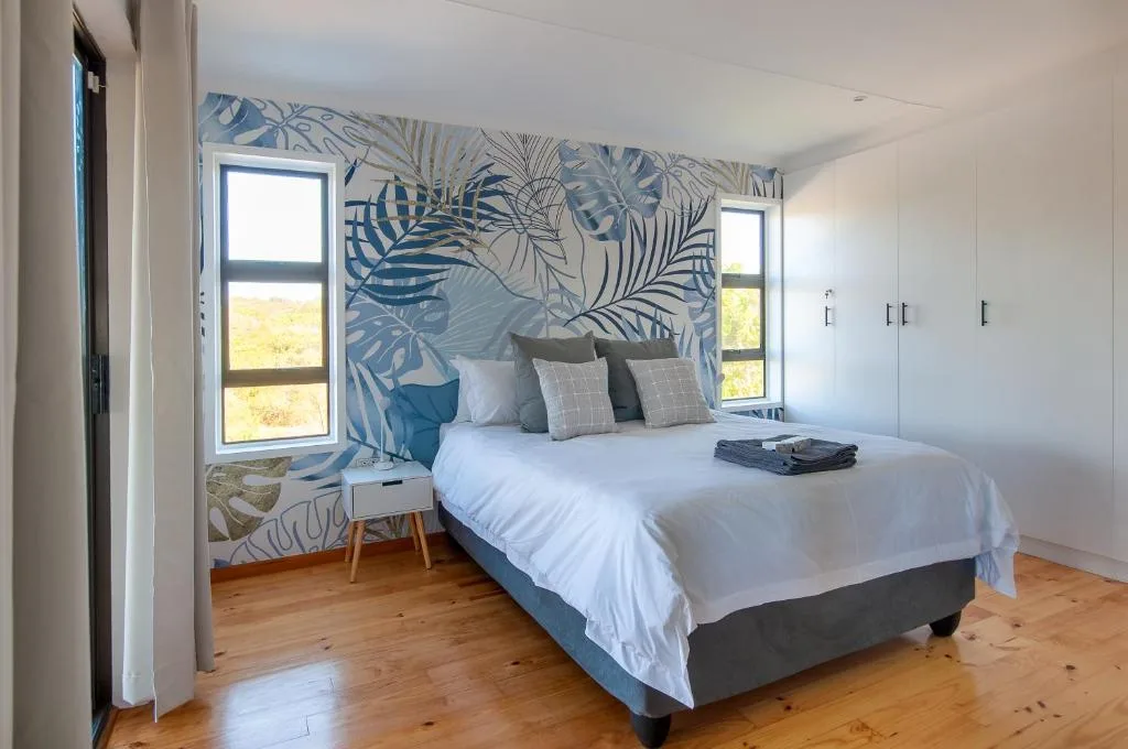 Modern bedroom with tropical palm wallpaper, white bedding, and garden views