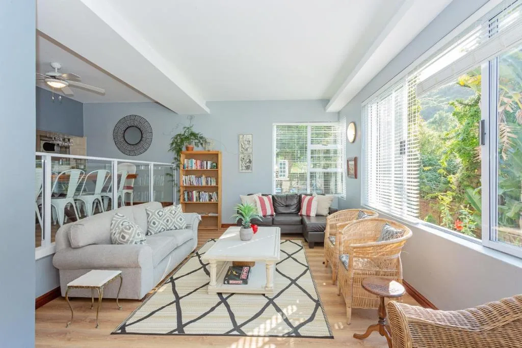 Bright living room with comfortable seating, large windows, and garden views