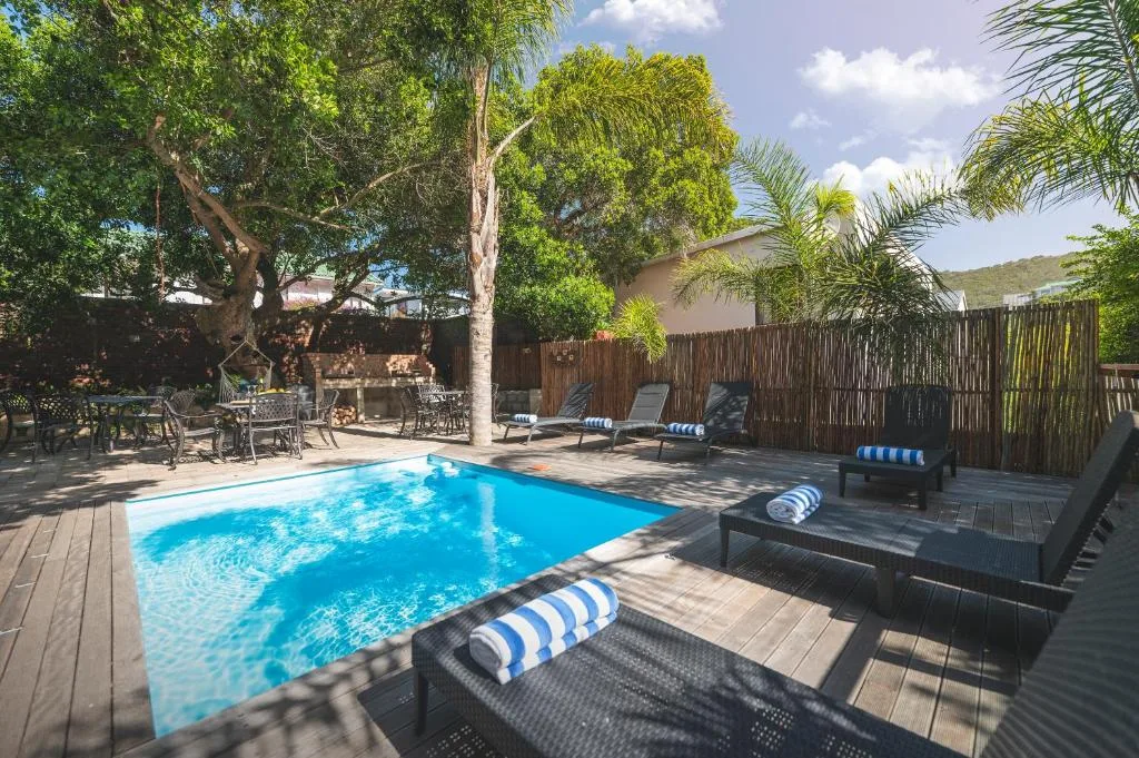 Swimming pool with loungers and trees in landscaped garden area