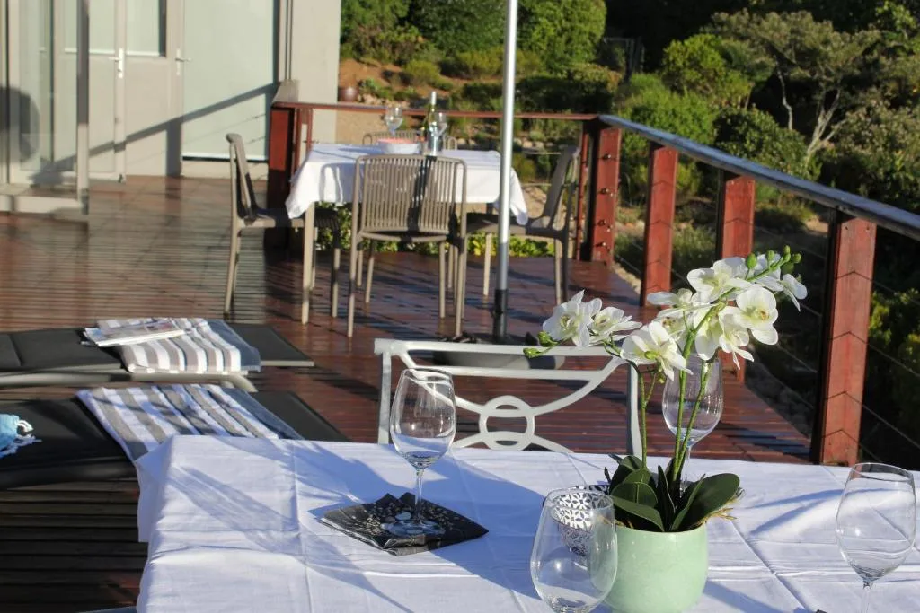 Wooden deck with dining table, loungers, and garden views