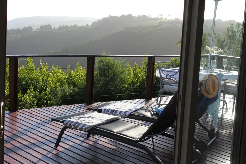 Wooden deck with loungers overlooking lush green hills and valley