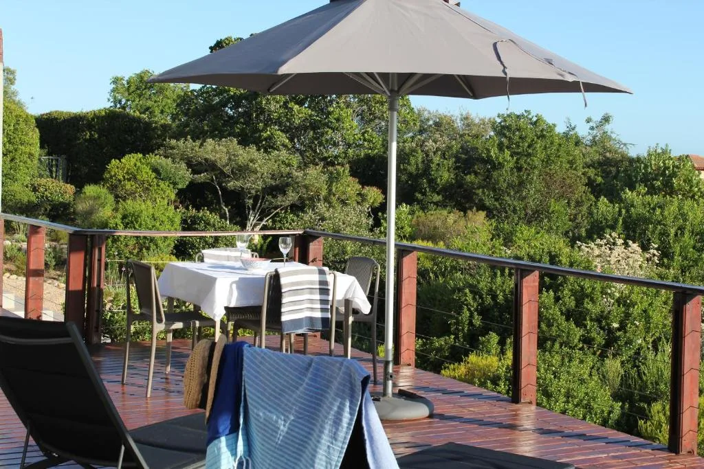 Wooden deck with dining table, umbrella, and garden views