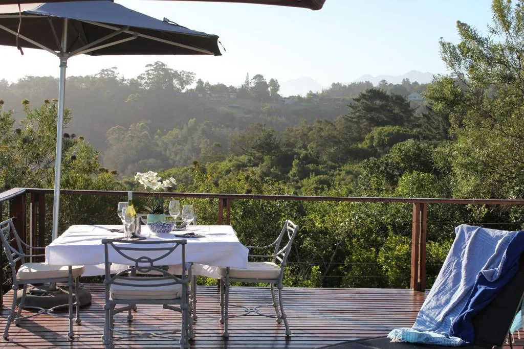 Wooden deck with dining table, umbrella, and forested mountain views