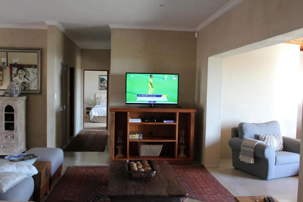 Living room with TV, wooden entertainment unit, armchair, and fireplace