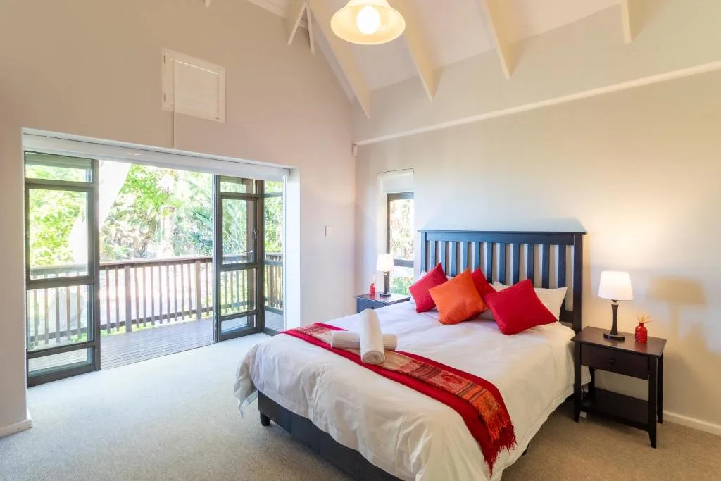 Bright bedroom with blue bed frame, red accents, and deck doors overlooking greenery
