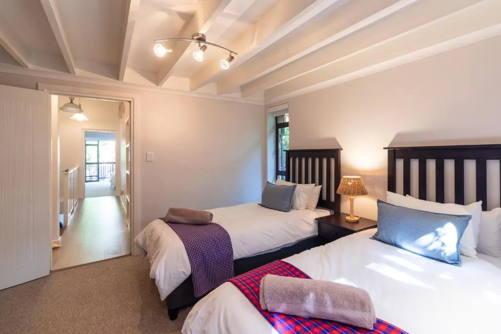 Bright bedroom with two queen beds, dark headboards, and modern ceiling lights
