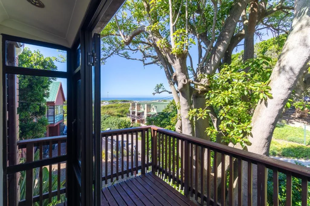 Dark wooden deck with railing overlooking coastal landscape and trees