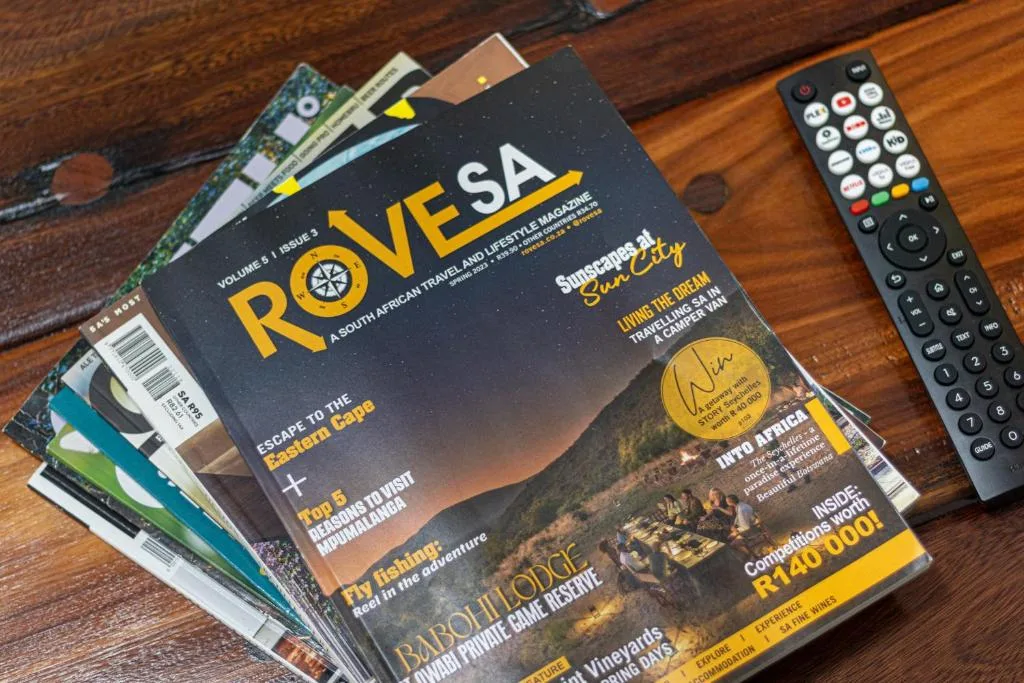 Travel magazines and remote control on wooden table surface