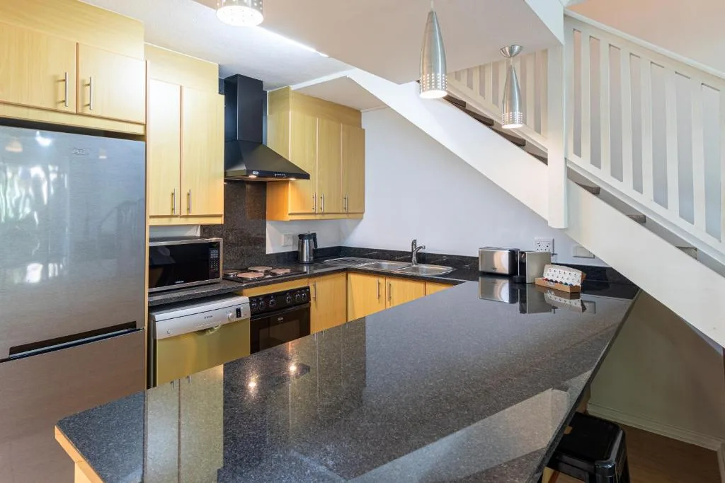 Modern kitchen with yellow cabinetry, dark countertops, and stainless steel appliances