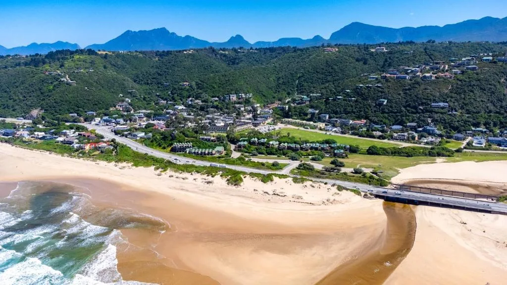 Aerial view of pristine beach, lagoon, and forested mountains beyond