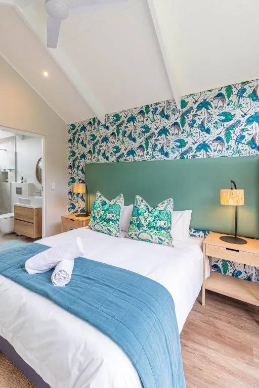 Bright bedroom with tropical wallpaper, queen bed, and green accent wall