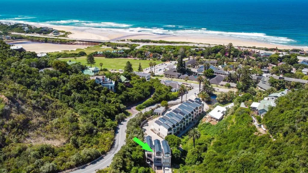 Aerial view of coastal property surrounded by lush vegetation overlooking sandy beach