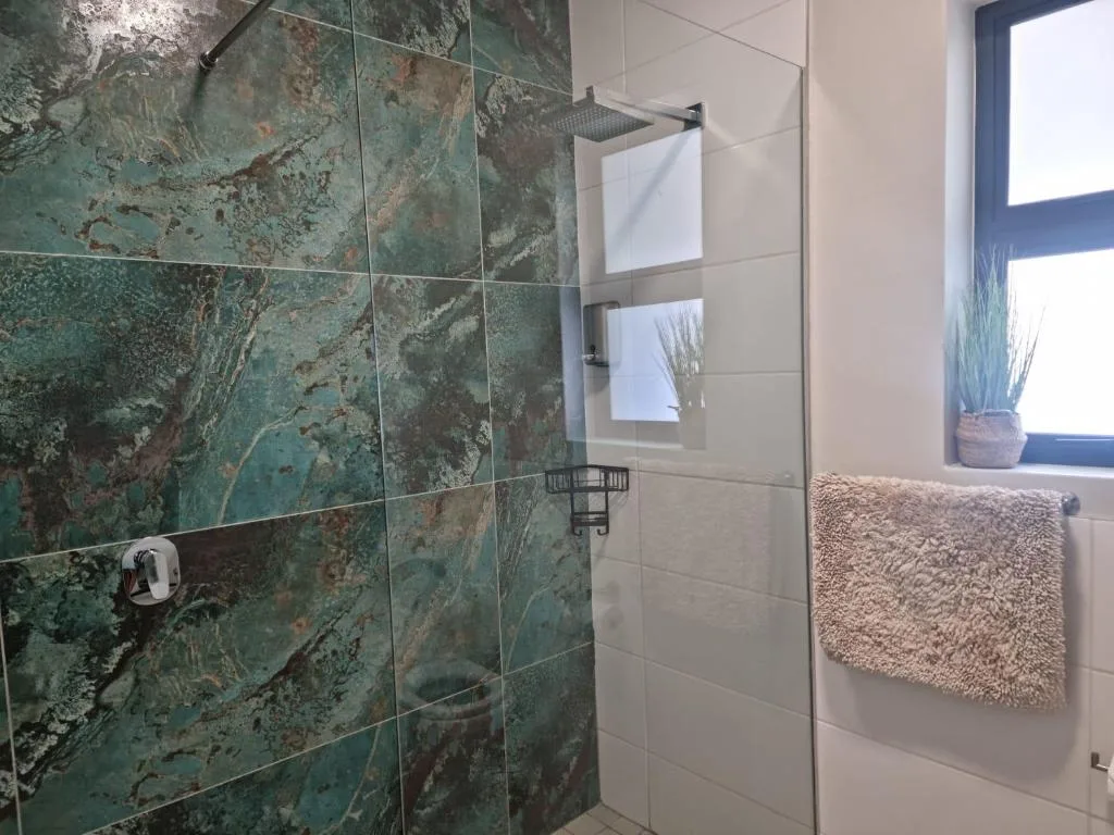 Modern bathroom with green marble tiled shower and heated towel rail