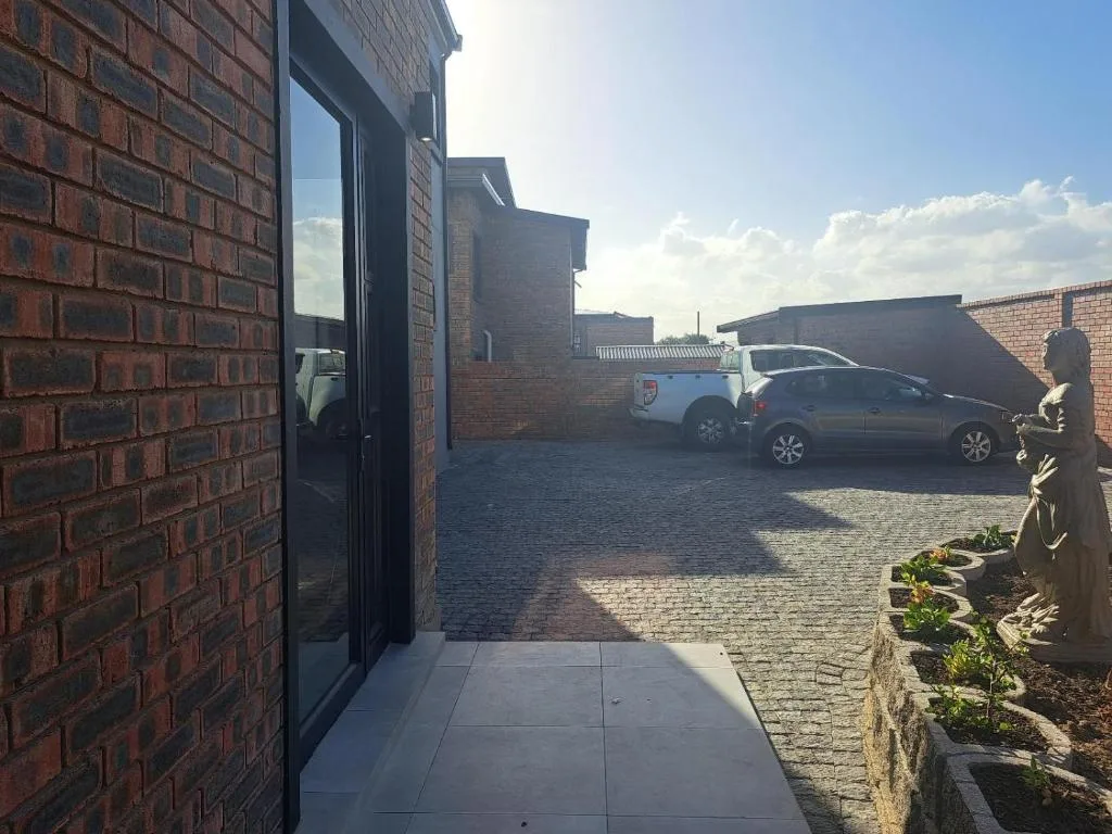Modern brick building entrance with paved driveway and parked cars