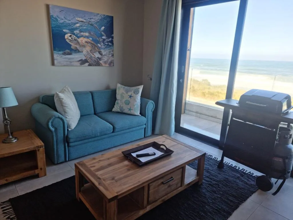 Blue sofa with ocean and beach view through sliding glass doors