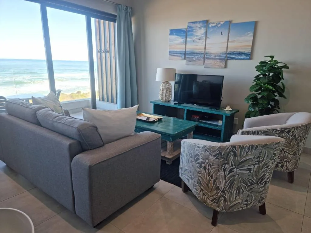 Spacious lounge with ocean views, comfortable seating, and coastal artwork
