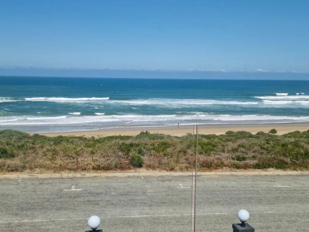 Pristine beach with rolling ocean waves and coastal vegetation from property